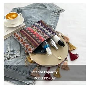 Detailed interior of ethnic woven bag with colorful tassels showing phone and spray storage