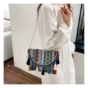Detail of bohemian woven bag featuring colorful fringe tassels and golden chain strap