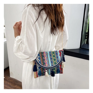 Bohemian woven crossbody bag with colorful patterns, blue tassels, and gold chain strap