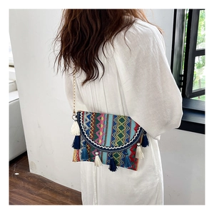 Detailed view of colorful ethnic weave shoulder bag with blue tassels and gold chain strap