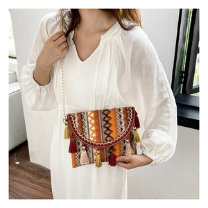 Close-up of ethnic style woven crossbody bag with colorful tassels and chain strap