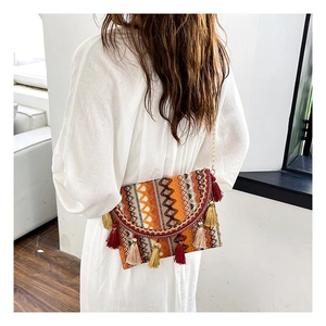 Detailed shot of ethnic woven crossbody bag with colorful tassels and gold chain strap