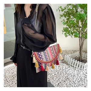 Detail of bohemian woven flap bag with colorful geometric patterns and fringe tassels