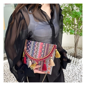 Detailed shot of ethnic plaid square bag with vibrant colorful tassels and metal chain