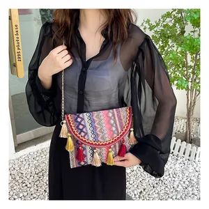Detailed view of woven ethnic crossbody bag with colorful tassels and gold chain strap