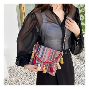 Close-up of bohemian woven crossbody bag with colorful tassels and gold chain strap