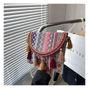 Detailed shot of ethnic woven bag with colorful fringe tassels and golden chain strap