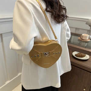 Sac bandoulière doré en forme de cœur avec finition métallisée et détail de nœud riveté