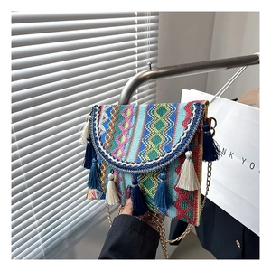 Detailed view of bohemian woven crossbody bag with colorful fringe and gold chain strap