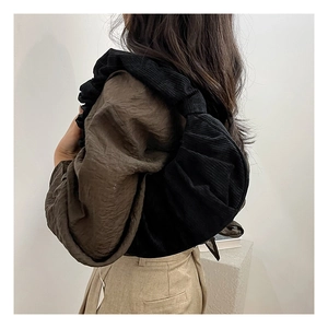 Gros plan du sac bandoulière en velours côtelé noir montrant la texture plissée sur modèle