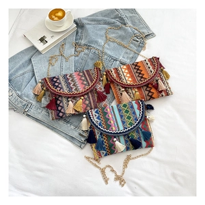 Detail of bohemian woven crossbody bags with colorful tassels and gold metal chain straps