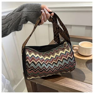 Detail of bohemian striped woven bag with wide geometric strap on a wooden table