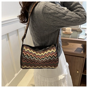 Ethnic striped crossbody bag with wide jacquard strap shown on a casual knitted sweater