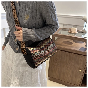 Close-up of a cylinder crossbody bag with colorful zigzag patterns and a wide shoulder strap