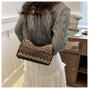 Ethnic crossbody bag with zigzag pattern and wide strap worn by a woman in a sweater