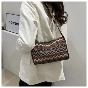 Close-up of retro zigzag woven crossbody bag with colorful stripes on a white blazer