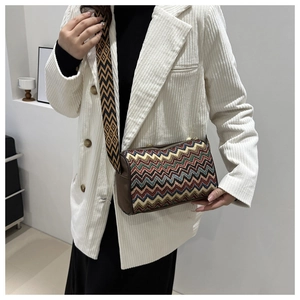 Close-up of ethnic crossbody bag with zigzag pattern and wide jacquard strap on a model