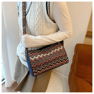 Close-up of colorful ethnic wave pattern crossbody bag with adjustable wide strap on a model