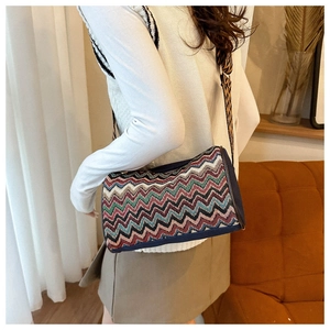 Close-up of colorful zigzag woven crossbody bag with wide strap on model in cozy interior