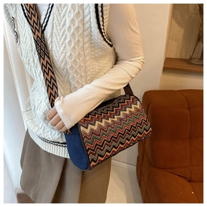 Detail of colorful zigzag knit crossbody bag with wide patterned strap and blue canvas