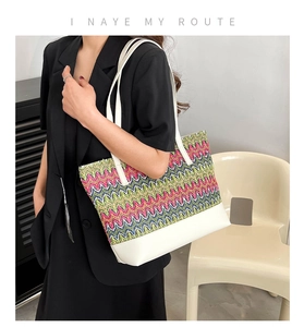 Close-up of woven tote bag with colorful wave patterns and white leather details