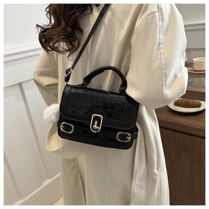 Detail of black crocodile texture bag with gold twist lock and white fur ball pendant