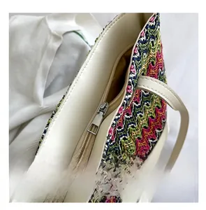 Detail of smooth metal zipper and white leather trim on bohemian woven tote bag