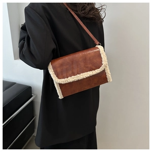 Close-up of retro brown PU leather shoulder bag with white faux fur trim on model