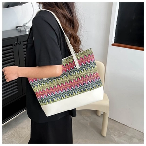 Detail of colorful woven tote bag featuring vibrant zigzag patterns and white PU leather strap