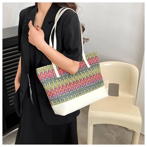 Detail of bohemian woven tote bag featuring colorful wave patterns and white handles