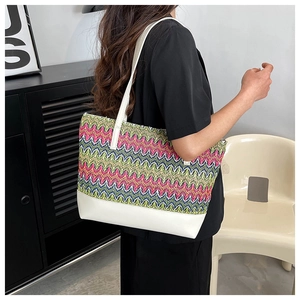 Detail of colorful woven straw tote bag with white leather straps and textured pattern