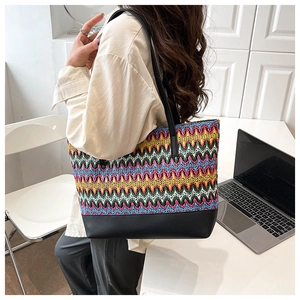 Detail of colorful woven tote bag with black faux leather shoulder strap and wave pattern