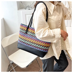 Detail view of large woven tote bag with colorful zigzag patterns and black leather base