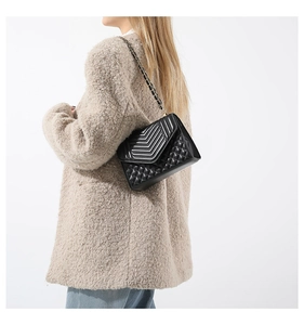 Détail d'un sac bandoulière noir matelassé avec surpiqûres en V et motifs en losanges