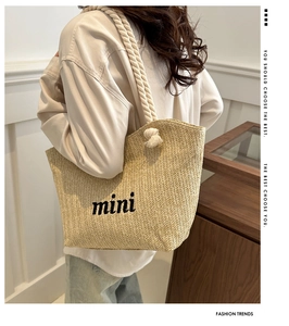Detail of woven straw shoulder bag with mini embroidery and thick cotton rope handles
