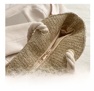 Detail view of woven straw tote bag featuring smooth gold zipper and rope handles