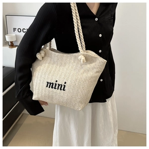 Detail of off-white woven straw shoulder bag featuring mini embroidery and rope handles