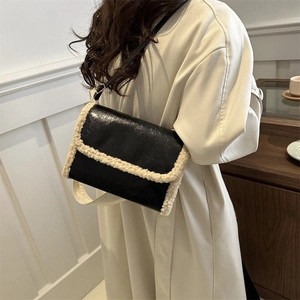Chic black PU leather crossbody bag with beige lamb wool trim in a cozy indoor setting