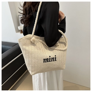 Detailed texture of beige woven straw bag with mini embroidery and cotton rope strap