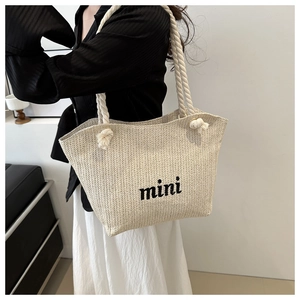 Detail of hand-woven straw tote bag with black mini embroidery and rope handles