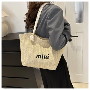Detail of hand-woven straw tote bag with black mini embroidery and soft cotton rope handles
