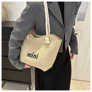 Detail of the straw woven shoulder bag featuring mini embroidery and white rope handle