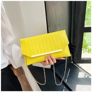 Nahaufnahme der gelben Umschlag-Clutch mit vertikaler Prägung und goldener Kette