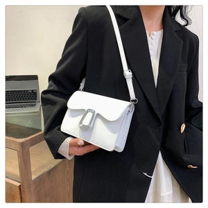 Close-up of minimalist white leather shoulder bag with a silver U-shaped metal buckle