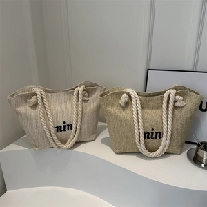 Minimalist straw woven tote bag with cotton rope handles and embroidered mini text