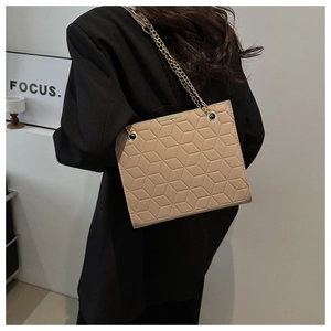 Detail of 3D geometric embossed texture and gold chain on beige faux leather bag