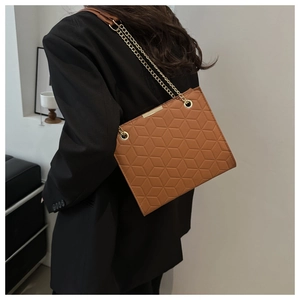 Brown geometric embossed leather crossbody bag worn with a black blazer for a stylish look