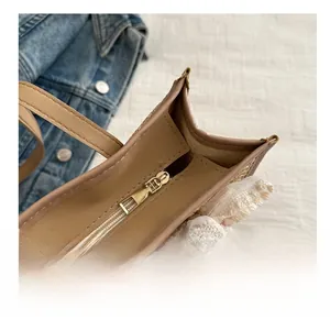 Detail of smooth metal zipper closure and floral lace trim on straw woven tote bag
