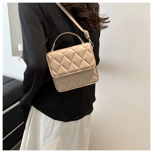 Sac bandoulière beige matelassé porté par un mannequin avec bandoulière et poignée