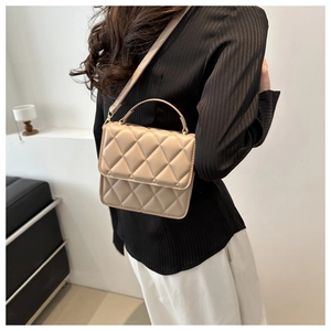 Détail d'un sac bandoulière matelassé beige avec fermoir métal et bandoulière fine